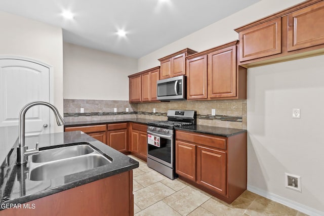 kitchen featuring appliances with stainless steel finishes, dark stone countertops, tasteful backsplash, and sink