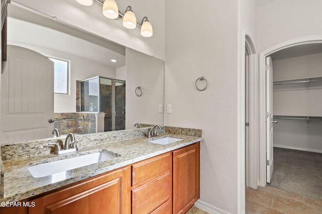 bathroom featuring a spacious closet, a stall shower, double vanity, and a sink