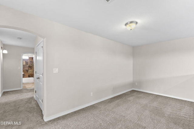 unfurnished room featuring baseboards, arched walkways, and carpet floors