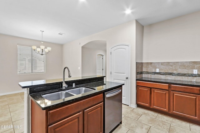 kitchen with a sink, dark stone counters, stainless steel dishwasher, and light tile patterned flooring