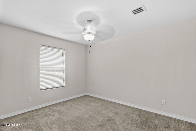 spare room featuring carpet flooring, a ceiling fan, visible vents, and baseboards