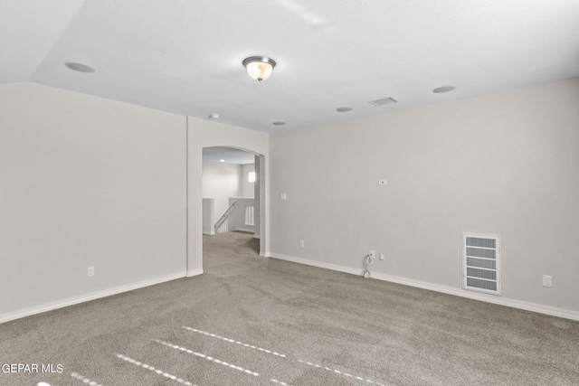 unfurnished room with visible vents, arched walkways, baseboards, and carpet flooring