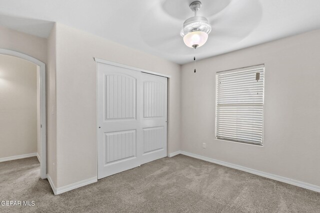 unfurnished bedroom with light carpet, ceiling fan, and a closet