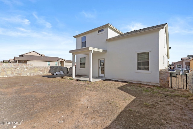 rear view of property with a patio area, fence, and stucco siding