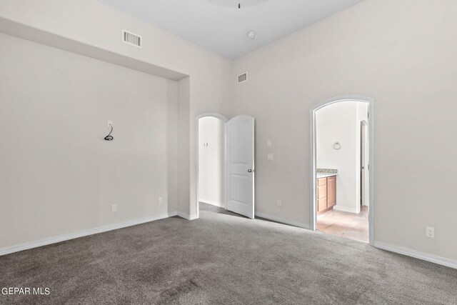 carpeted empty room featuring a high ceiling