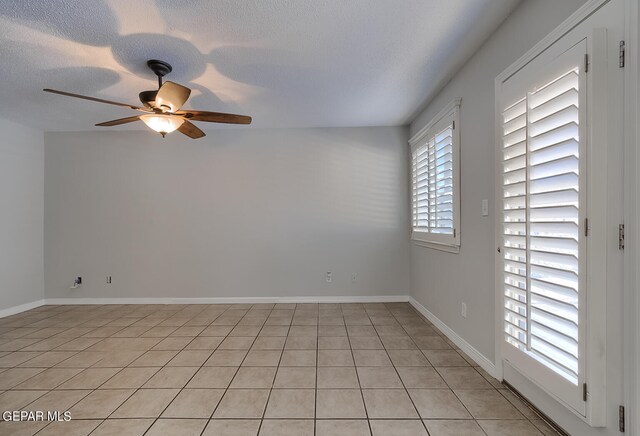 tiled spare room featuring a textured ceiling, a healthy amount of sunlight, and ceiling fan