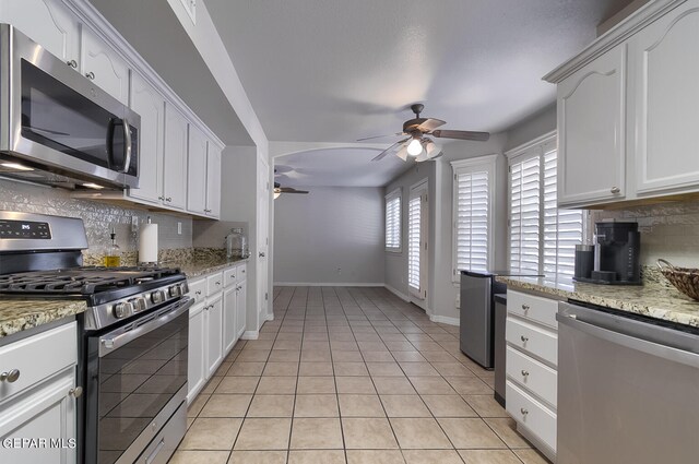 kitchen featuring stainless steel appliances, decorative backsplash, ceiling fan, light stone counters, and white cabinets