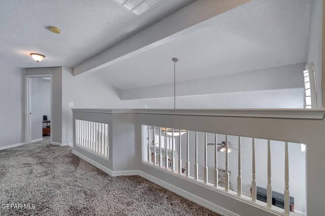 corridor with lofted ceiling with beams, a textured ceiling, and carpet floors