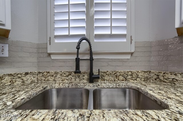 room details featuring light stone countertops, white cabinetry, and sink