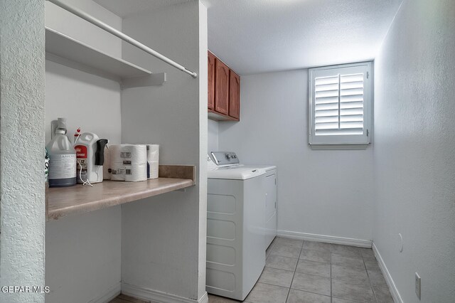 clothes washing area featuring light tile patterned floors, a textured ceiling, cabinets, and washer and dryer