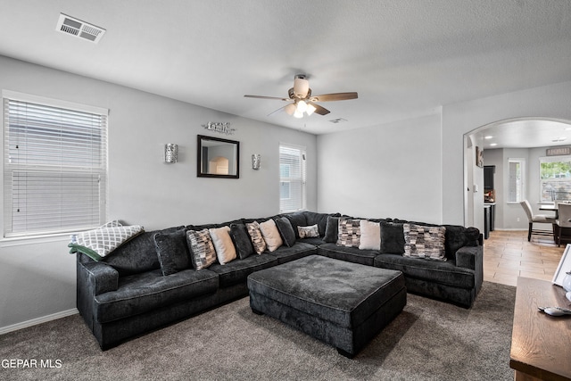 carpeted living room with a textured ceiling and ceiling fan