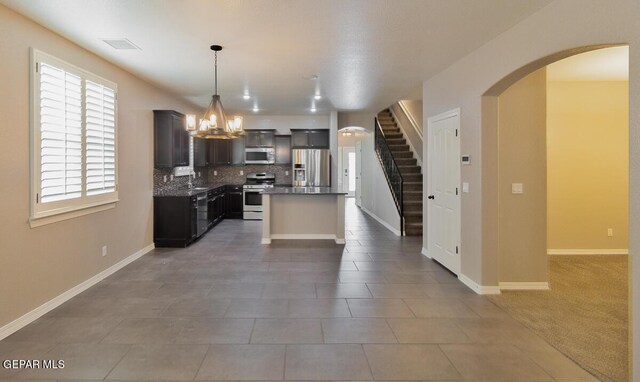 kitchen with pendant lighting, a center island, stainless steel appliances, decorative backsplash, and a chandelier