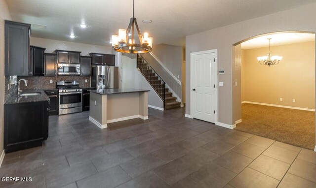 kitchen featuring pendant lighting, a kitchen island, an inviting chandelier, sink, and appliances with stainless steel finishes