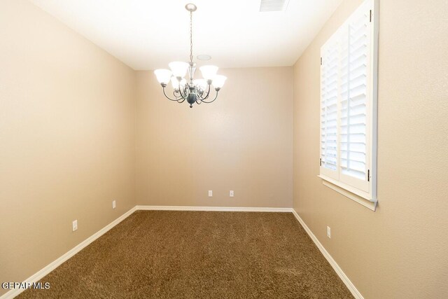 carpeted spare room with a chandelier