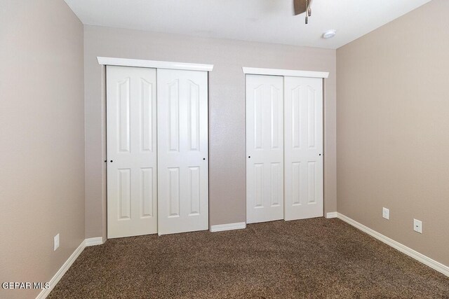 unfurnished bedroom featuring ceiling fan, carpet, and multiple closets