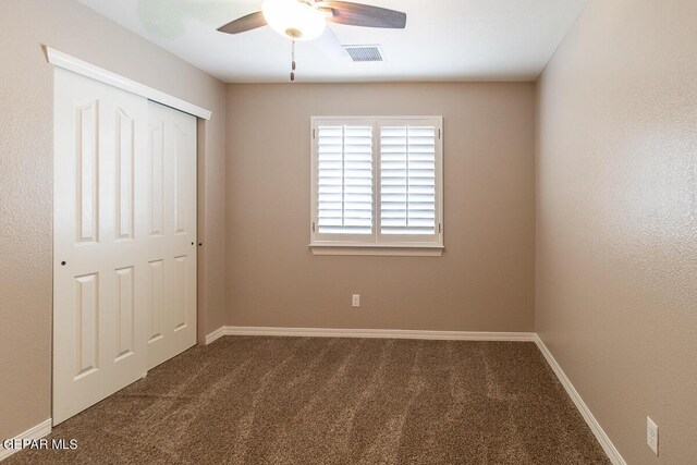 unfurnished bedroom with dark carpet, ceiling fan, and a closet