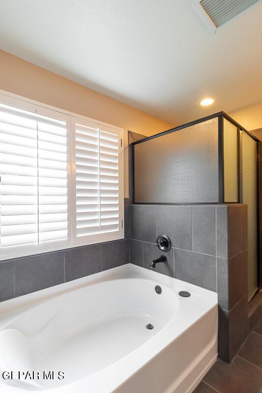 bathroom featuring tile patterned flooring and shower with separate bathtub