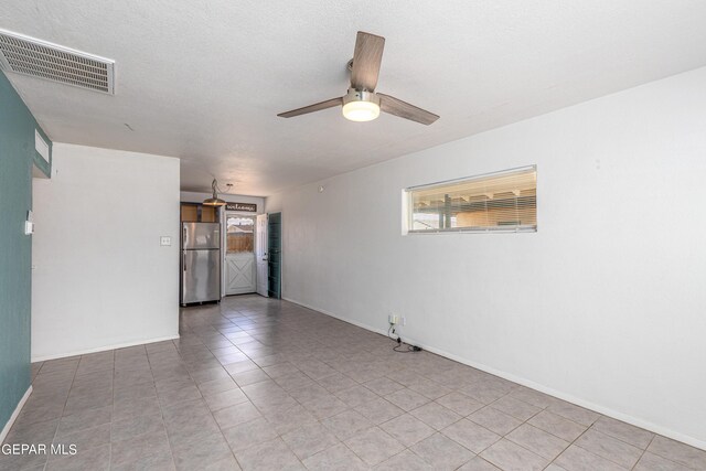 tiled empty room featuring a textured ceiling and ceiling fan