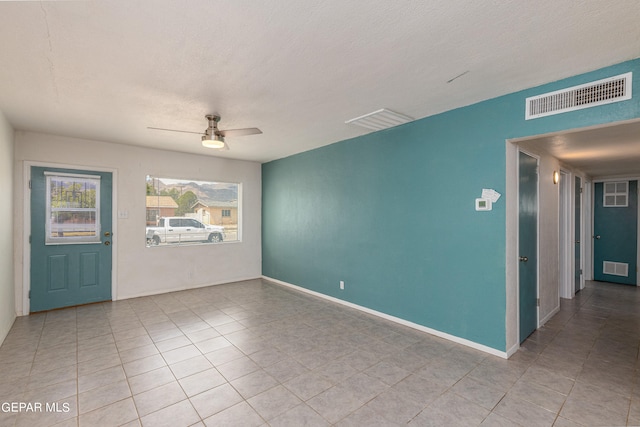 unfurnished room with a textured ceiling, light tile patterned flooring, and ceiling fan