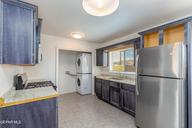 kitchen with light tile patterned floors, stainless steel appliances, sink, stacked washer / dryer, and dark brown cabinetry