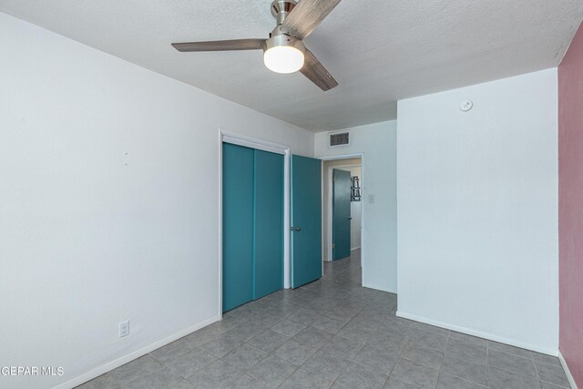 empty room with ceiling fan and a textured ceiling