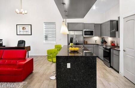 kitchen featuring dark countertops, light wood finished floors, stainless steel fridge with ice dispenser, gray cabinetry, and gas range