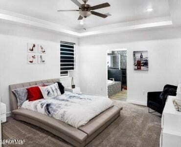 carpeted bedroom with a tray ceiling and ceiling fan