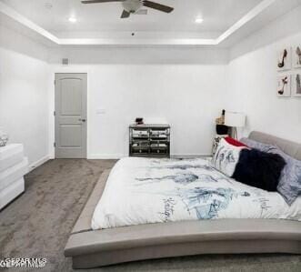 carpeted bedroom featuring ceiling fan and a tray ceiling