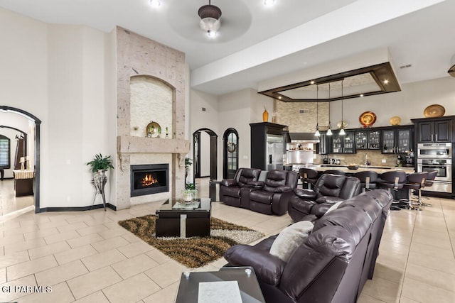 interior space featuring a high ceiling, ceiling fan, a fireplace, and light tile patterned flooring