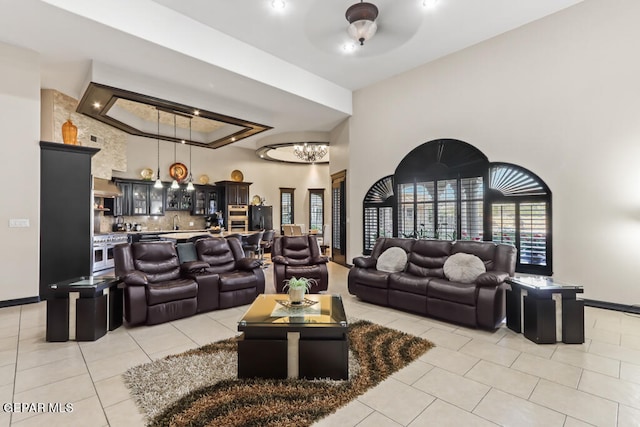 living room featuring ceiling fan with notable chandelier, a towering ceiling, and light tile patterned floors