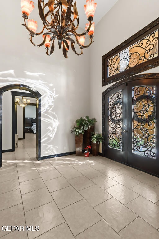 entrance foyer featuring an inviting chandelier, light tile patterned flooring, and french doors