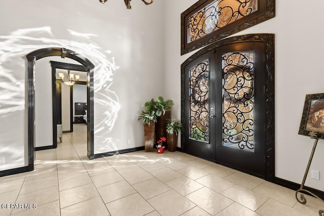 tiled entrance foyer with a chandelier and french doors