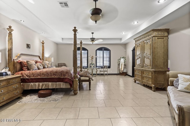 tiled bedroom with a raised ceiling and ceiling fan