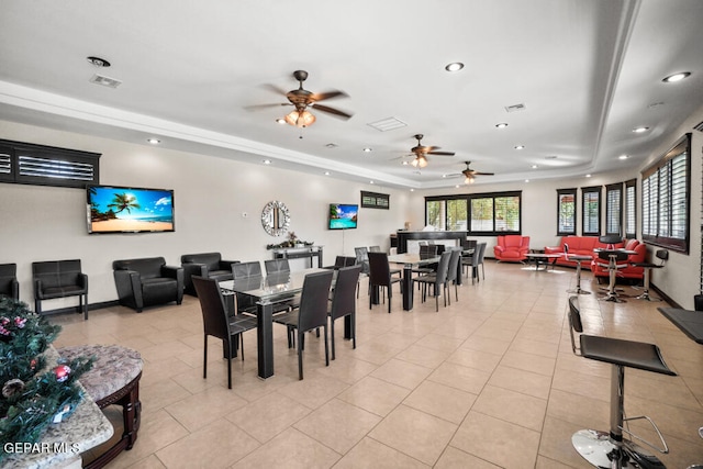 dining area featuring ceiling fan, light tile patterned floors, and a raised ceiling