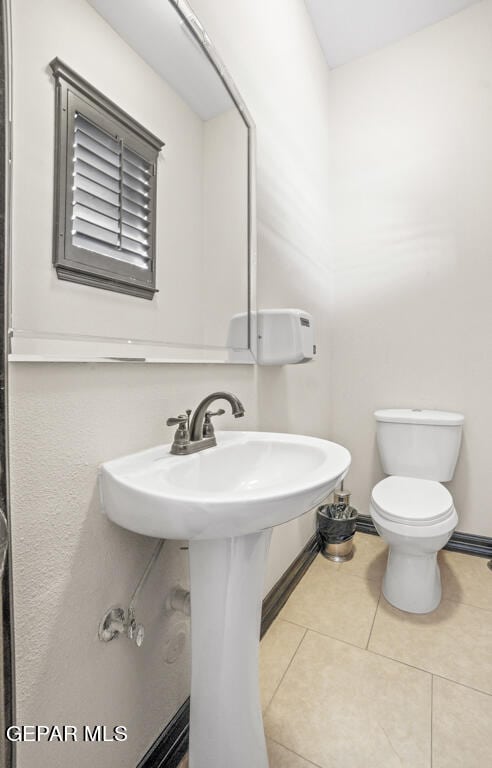 bathroom with toilet, sink, and tile patterned floors