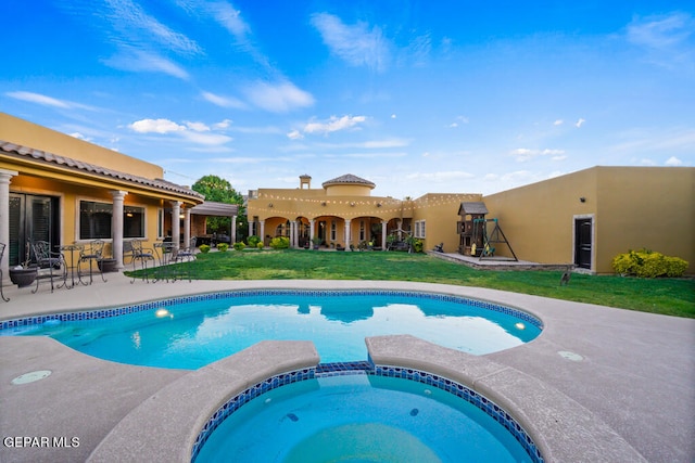 view of pool featuring an in ground hot tub, a lawn, and a patio