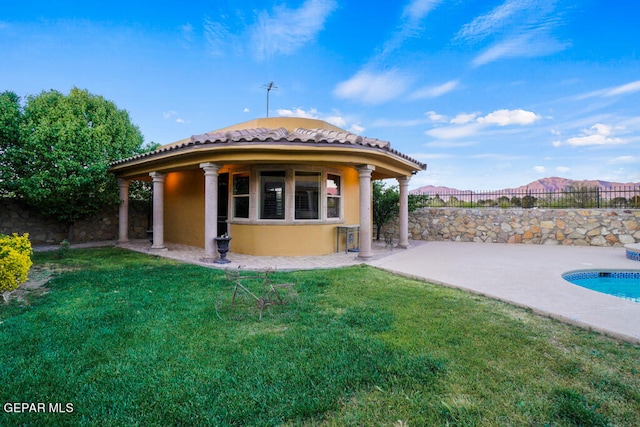 back of property with a fenced in pool, a patio area, and a yard