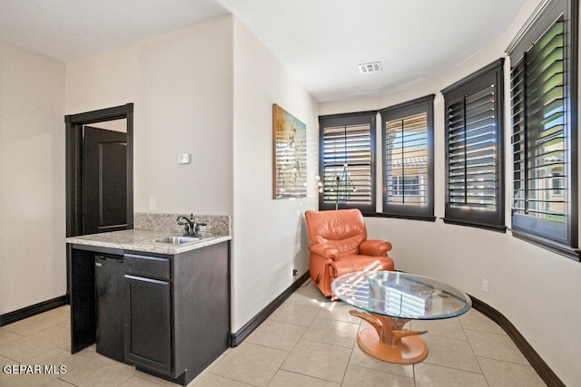 interior space with dishwasher, light stone counters, light tile patterned flooring, and sink