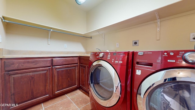 washroom featuring washer and dryer, light tile patterned floors, and cabinets