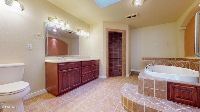 bathroom with tiled tub, tile patterned flooring, vanity, and toilet