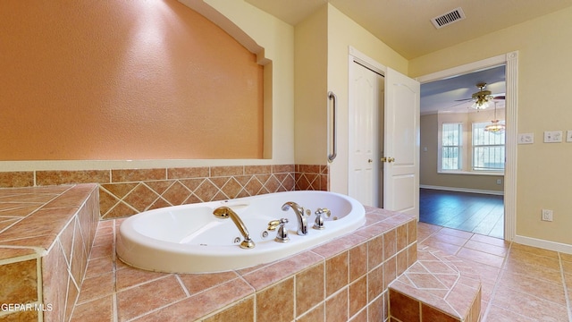 bathroom with hardwood / wood-style flooring, ceiling fan, and tiled tub