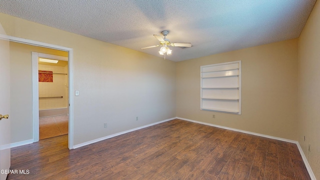 unfurnished room featuring a textured ceiling, dark hardwood / wood-style flooring, built in features, and ceiling fan