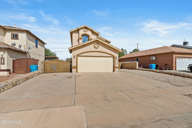 view of front of home with stucco siding, a gate, central AC, concrete driveway, and a garage