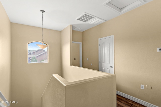 hallway with visible vents, an upstairs landing, baseboards, and dark wood finished floors