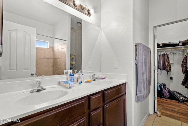 full bathroom featuring a spacious closet, walk in shower, double vanity, tile patterned floors, and a sink