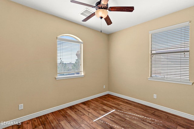 empty room featuring hardwood / wood-style floors, visible vents, a ceiling fan, and baseboards