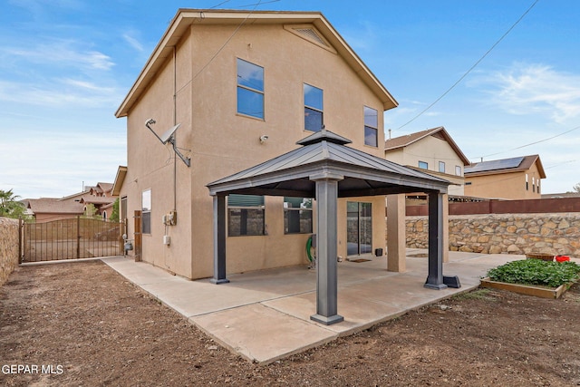 back of house featuring a patio, a gate, a fenced backyard, and stucco siding