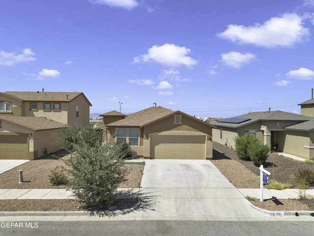 view of front of house with stucco siding, a garage, and driveway