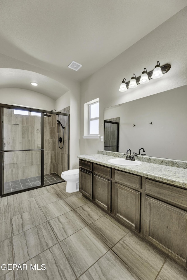 bathroom featuring visible vents, vanity, toilet, and a shower stall