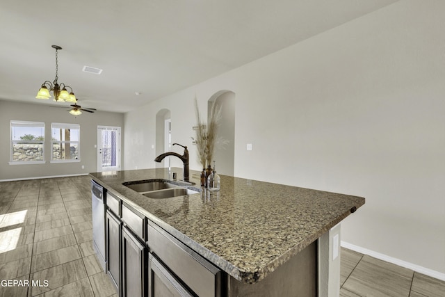 kitchen with a sink, decorative light fixtures, stainless steel dishwasher, open floor plan, and arched walkways